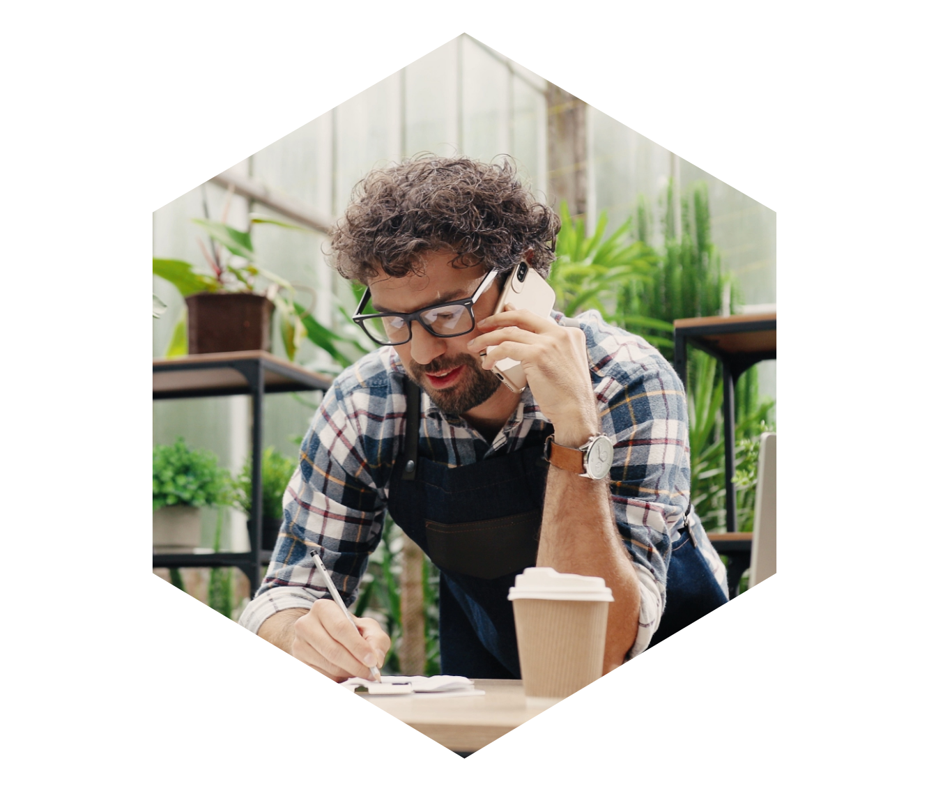 man in plant shop on the phone and writing notes