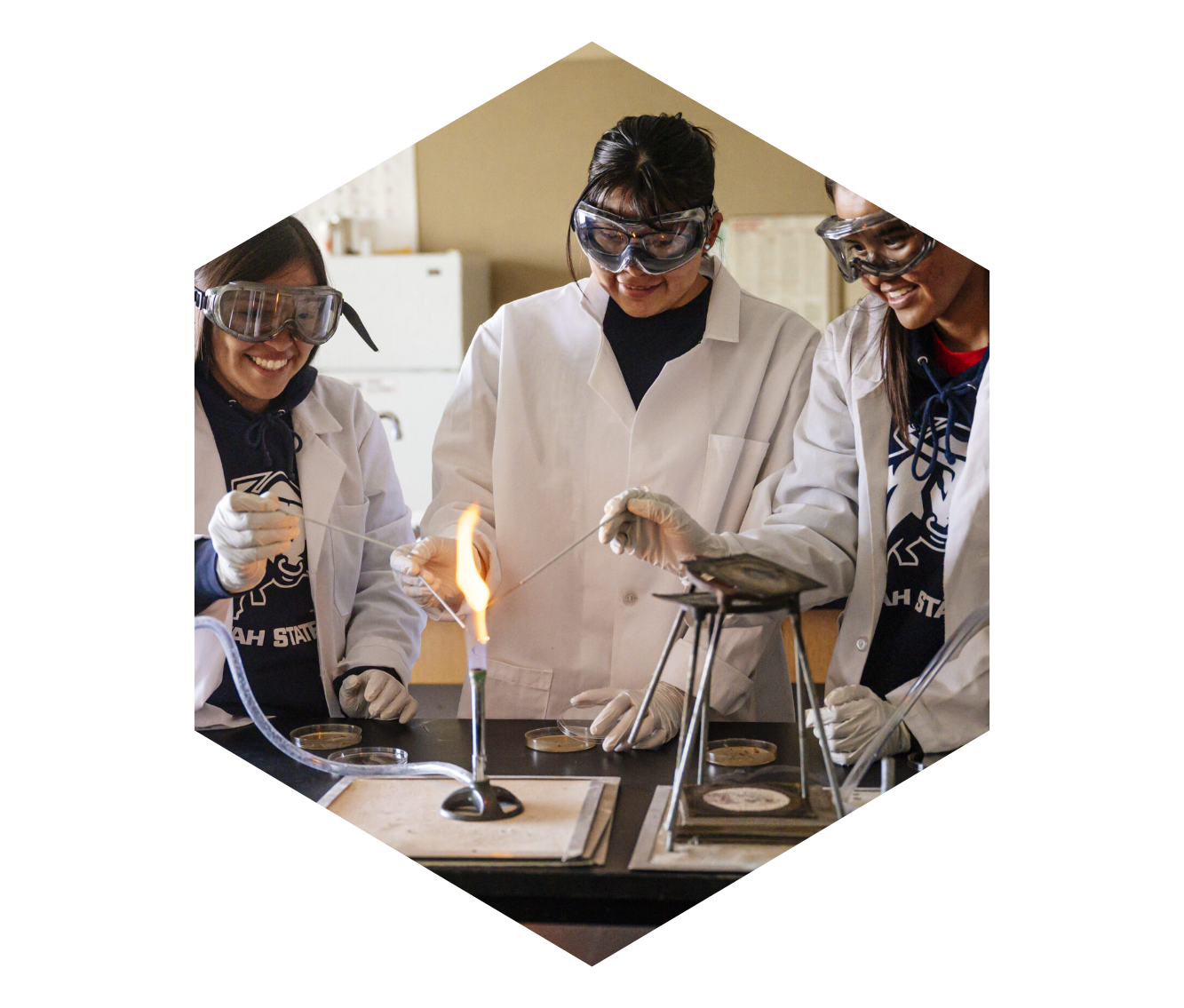 three girls doing a science experiment with a bunson burner
